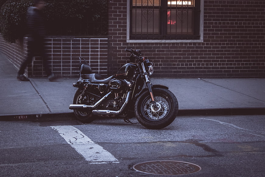 Black motorcycle parked on city street with brick building background