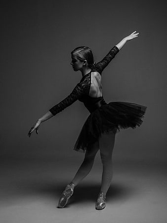 Ballerina in black tutu performing ballet pose in studio