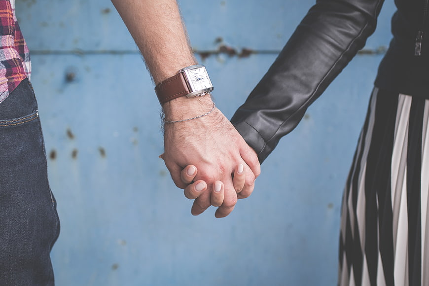 Couple Holding Hands Against Blue Wall