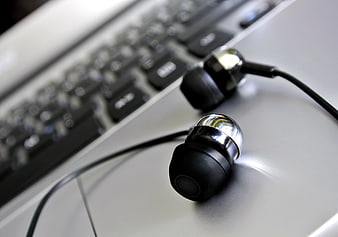 Close-up of black earbuds on a silver laptop