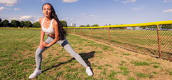 Athletic woman stretching on grassy field outdoors
