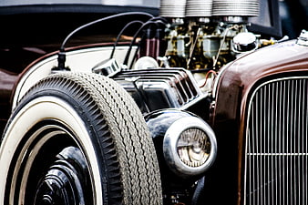 Close-up of vintage car engine, chrome headlight, and whitewall tire