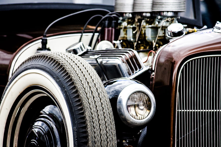 Close-up of vintage car engine, chrome headlight, and whitewall tire