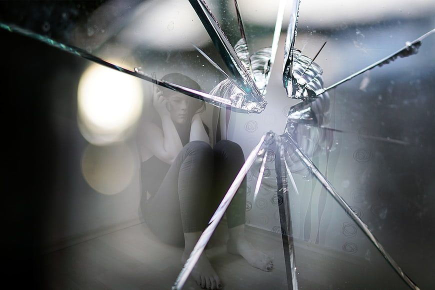 Woman behind shattered glass representing anxiety and fear