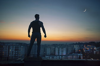 Silhouette of Man Standing on Rooftop at Sunset