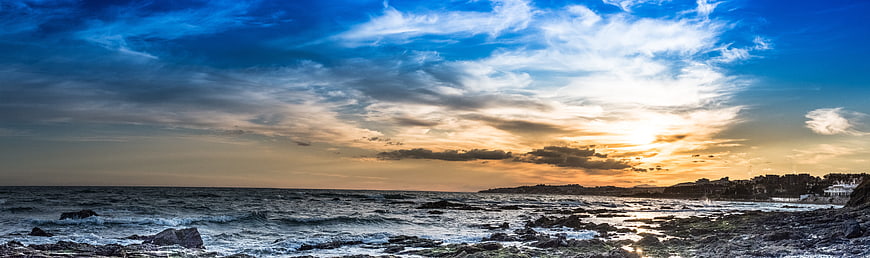 Panoramic sunset over rocky coastal landscape with dramatic clouds