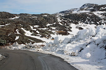 Winding mountain road with snowbanks in winter landscape