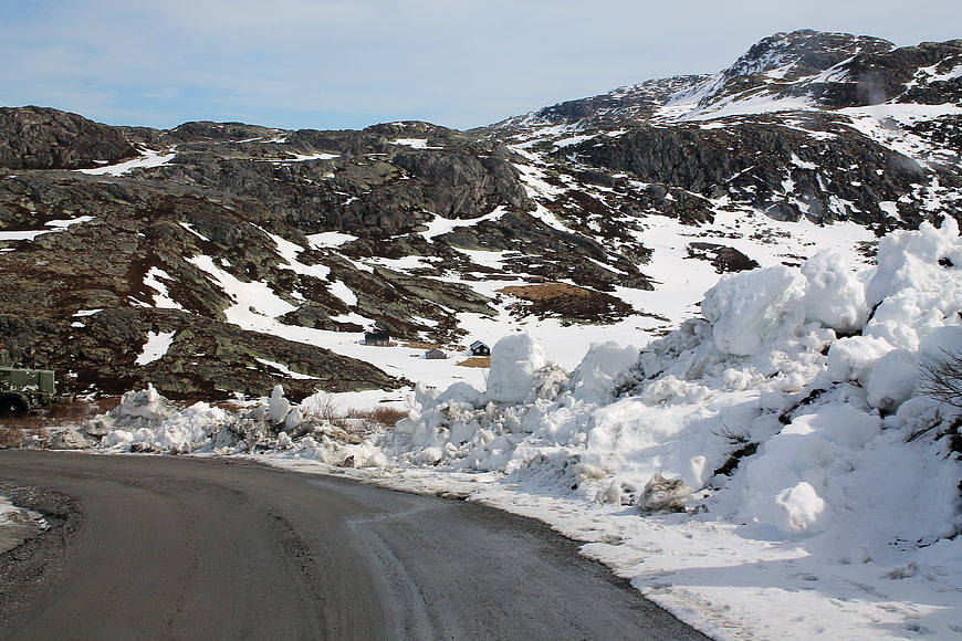 Winding mountain road with snowbanks in winter landscape