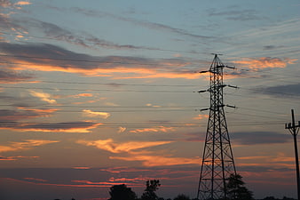 Silhouette of electricity pylon against colorful sunset sky