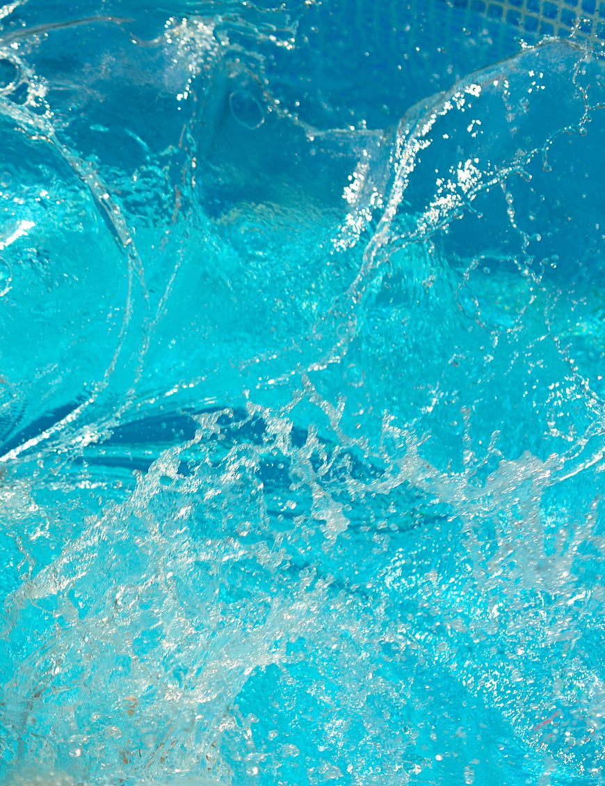 Close-up of vibrant blue pool water splash with bubbles