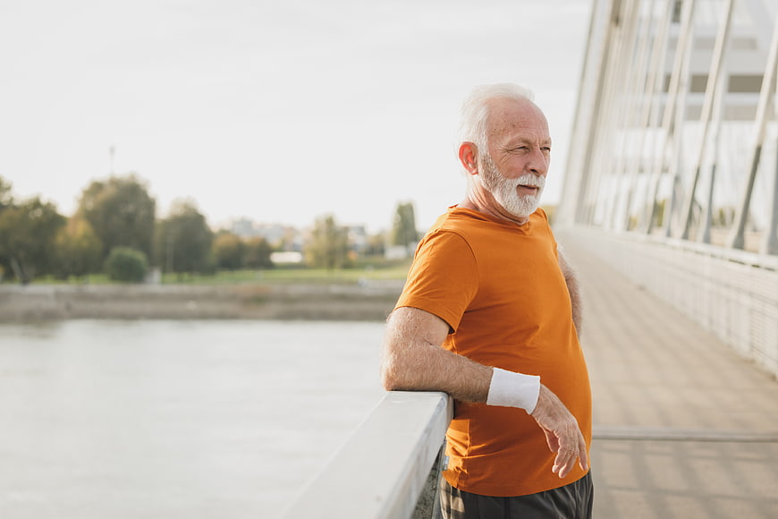 Senior man resting after running on bridge