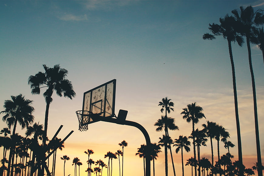 Silhouette of Basketball Hoop and Palm Trees at Sunset