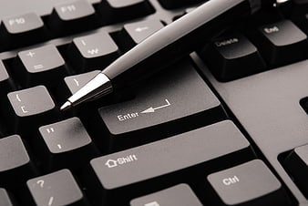 Close-up of black pen resting on computer keyboard enter key