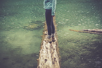 Woman balancing on log in clear green river water