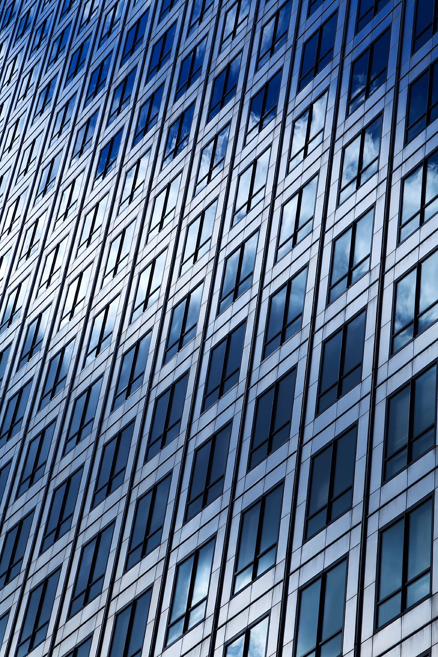 Modern Skyscraper Facade with Blue Glass Windows and Cloud Reflections