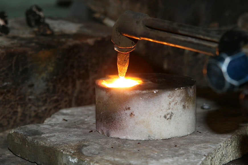Close-up of welding torch heating metal on industrial workbench