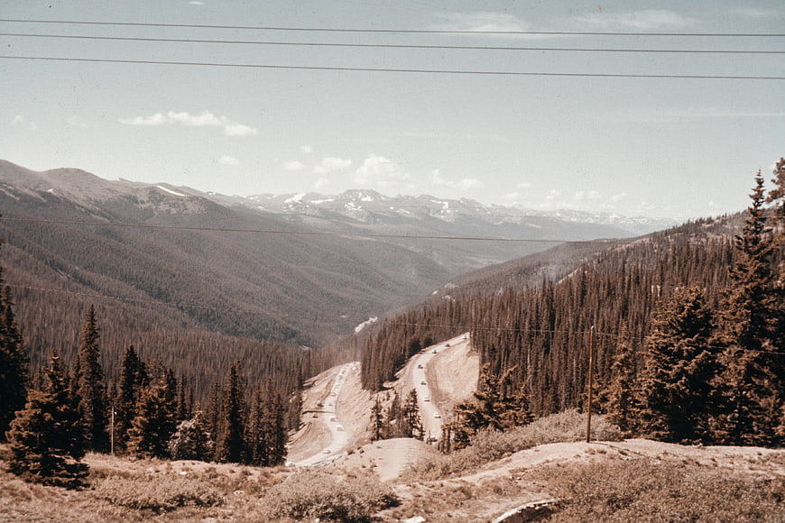 Vintage mountain highway landscape with winding road and pine forest