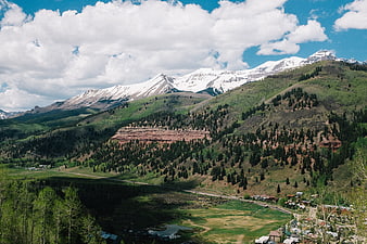 Snow-Capped Mountain Range Overlooking Green Valley and Town
