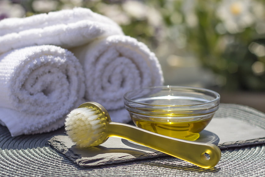 Spa towels, massage oil, and brush on slate