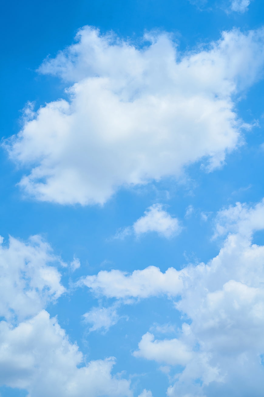 Fluffy white clouds against a bright blue sky background
