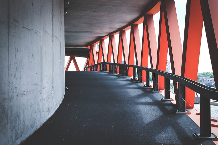 Modern orange steel bridge structure with concrete wall