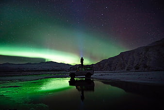 Silhouette of Man on Jeep Under Aurora Borealis
