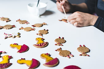 Hands decorating Easter bunny gingerbread cookies on white table