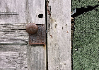 Close-up of weathered wooden door with rusty latch