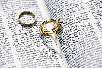 Gold wedding rings on open bible pages