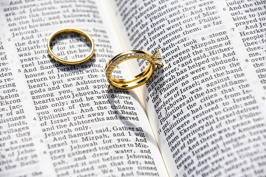 Gold wedding rings on open bible pages