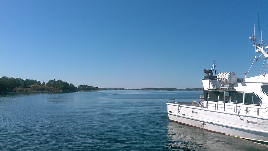 White boat docked in calm blue sea with forested islands