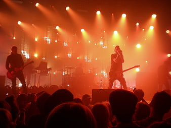 Rock band performing live on stage with orange lighting