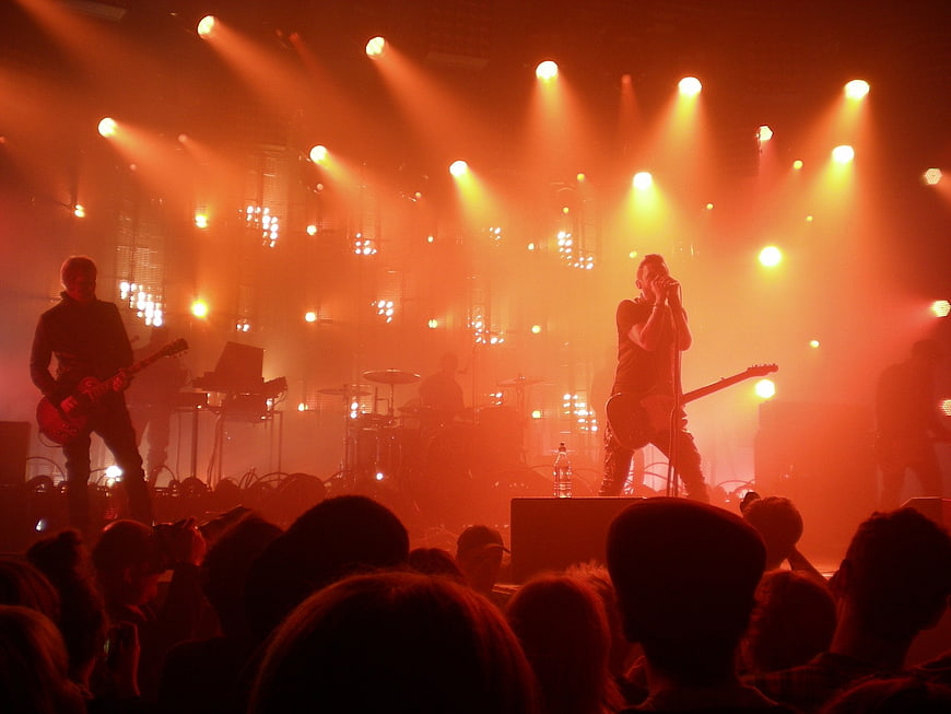Rock band performing live on stage with orange lighting