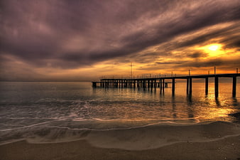 Dramatic Sunset Over Ocean Pier With Moody Clouds
