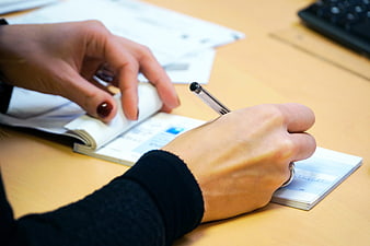 Woman's hands writing on a check at a desk