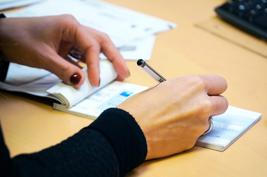 Woman's hands writing on a check at a desk