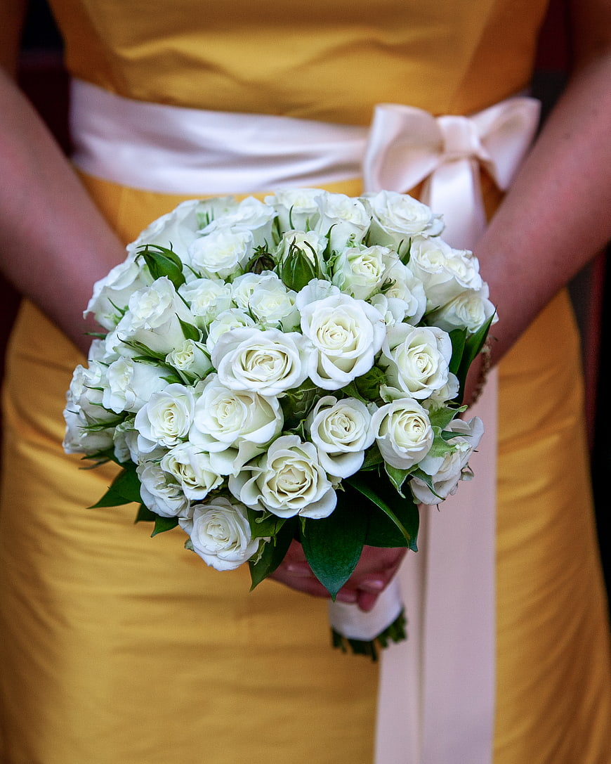 Bridesmaid holding white rose bouquet in yellow dress