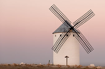White windmill against pink sunset sky in arid landscape