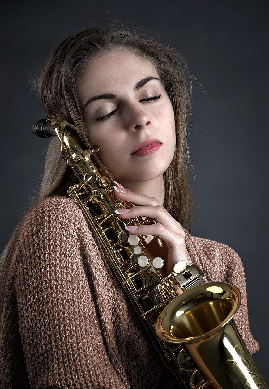 Woman with closed eyes holding a golden saxophone