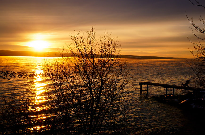 Golden Sunset Over Lake with Silhouetted Dock and Trees