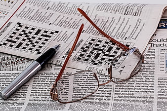Reading glasses and pen on newspaper crossword puzzle