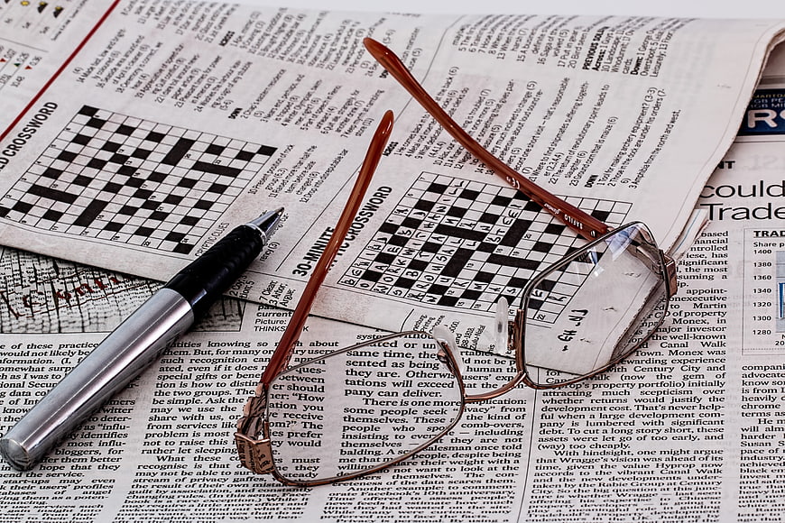 Reading glasses and pen on newspaper crossword puzzle