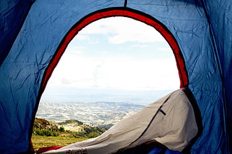 View from inside a blue camping tent overlooking a valley