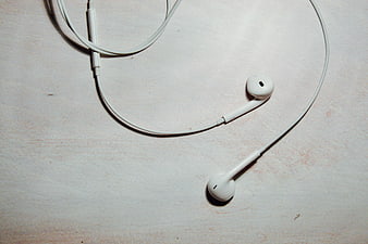 White Wired Earbuds on Textured Surface