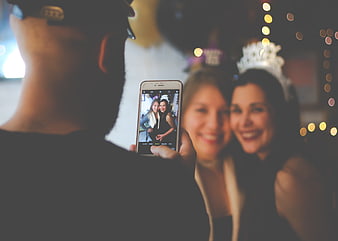 Man taking photo of two smiling women at a party