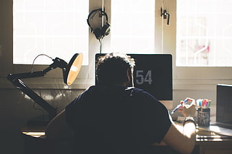 Man working at desk with computer and lamp in home office