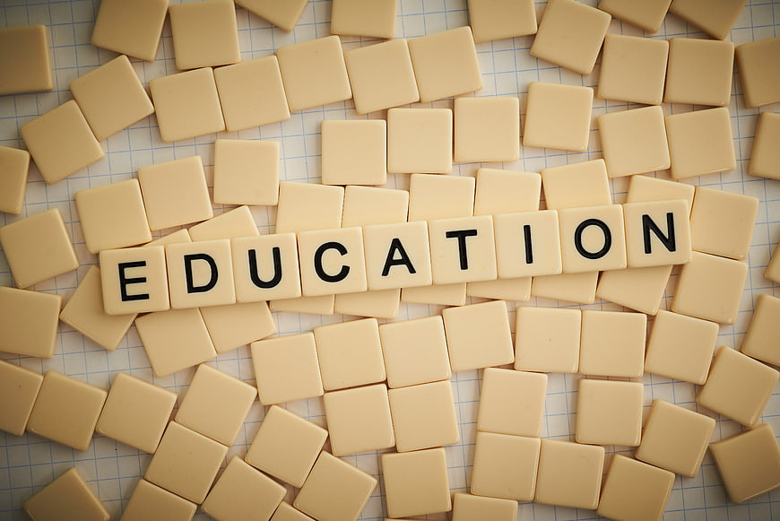 Education spelled with wooden letter tiles on graph paper