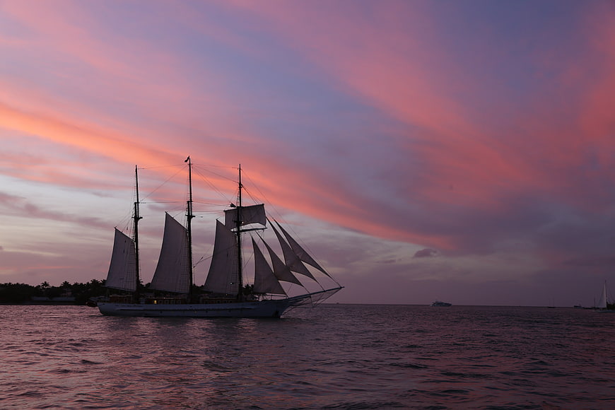 Tall Sailing Ship Silhouette Against Vibrant Pink Sunset Sky