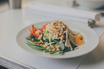 Fresh vegetable salad with egg and nuts on white plate