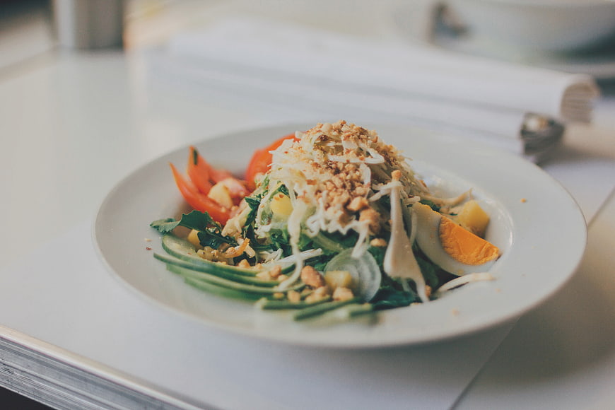 Fresh vegetable salad with egg and nuts on white plate